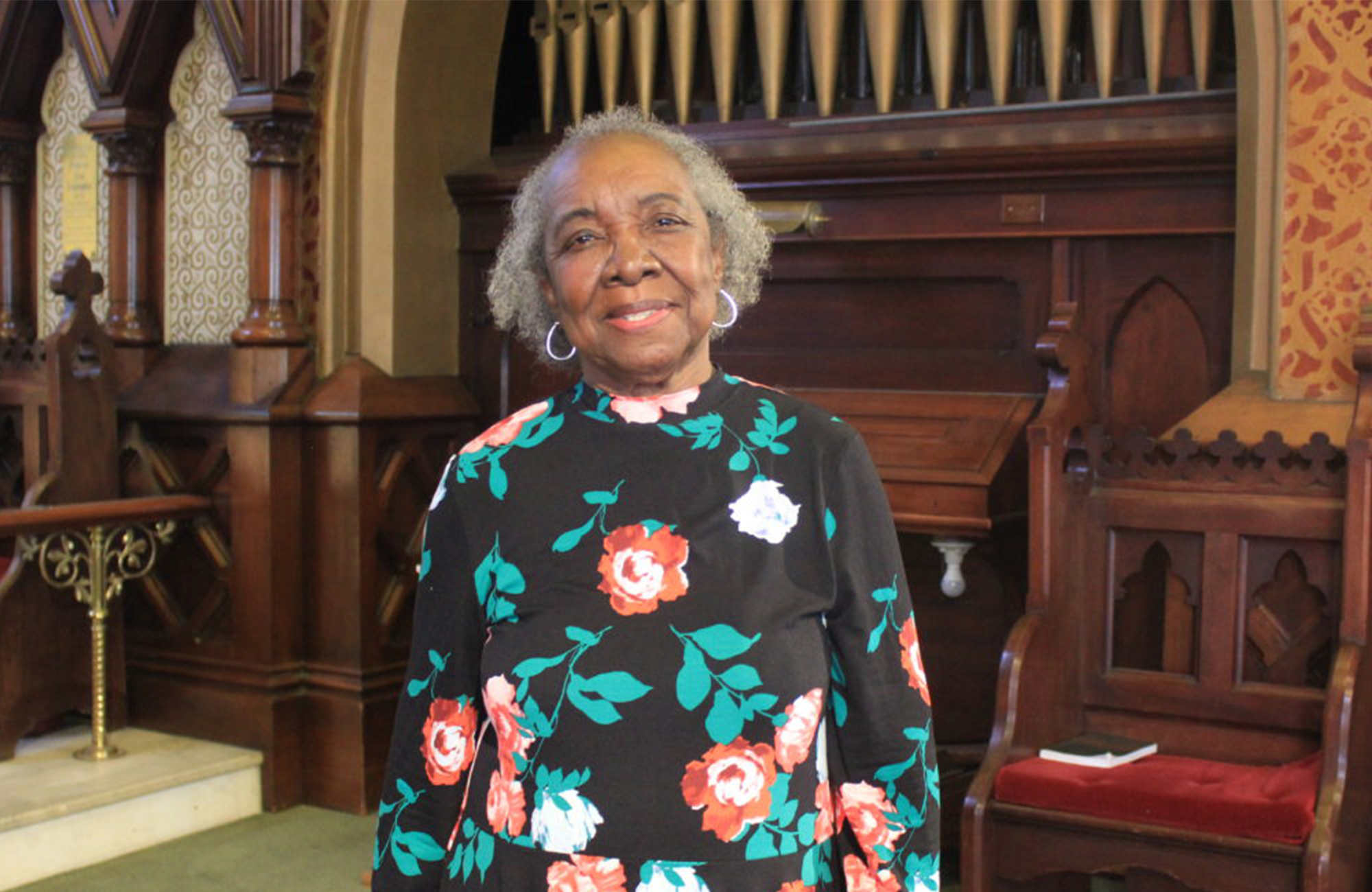 Image of Dr. Joan Hillsman in front of church organ pipes