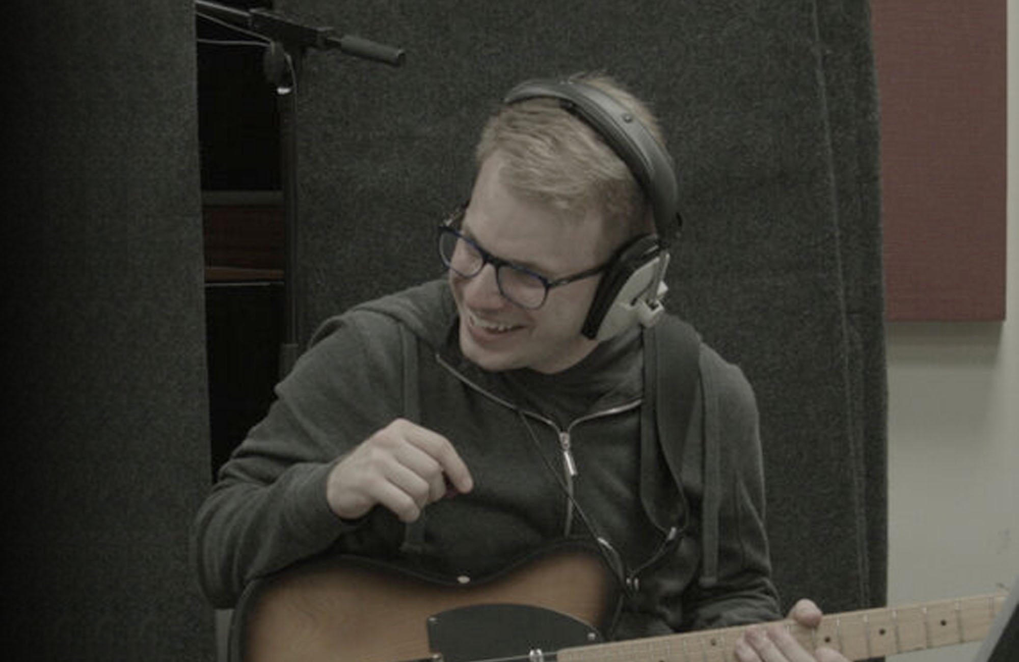 image of Chris Cresswell holding guitar and wearing headphones